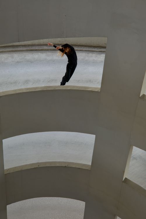 Free A dancer in black clothes performs on a concrete structure in an urban environment. Stock Photo