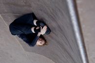 Woman in Blue Long Sleeve Shirt and Black Pants Standing on Gray Concrete Floor