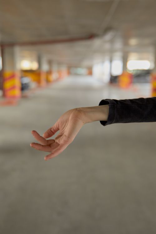 Free Close-up of a hand making an expressive gesture in a parking garage, capturing urban art. Stock Photo
