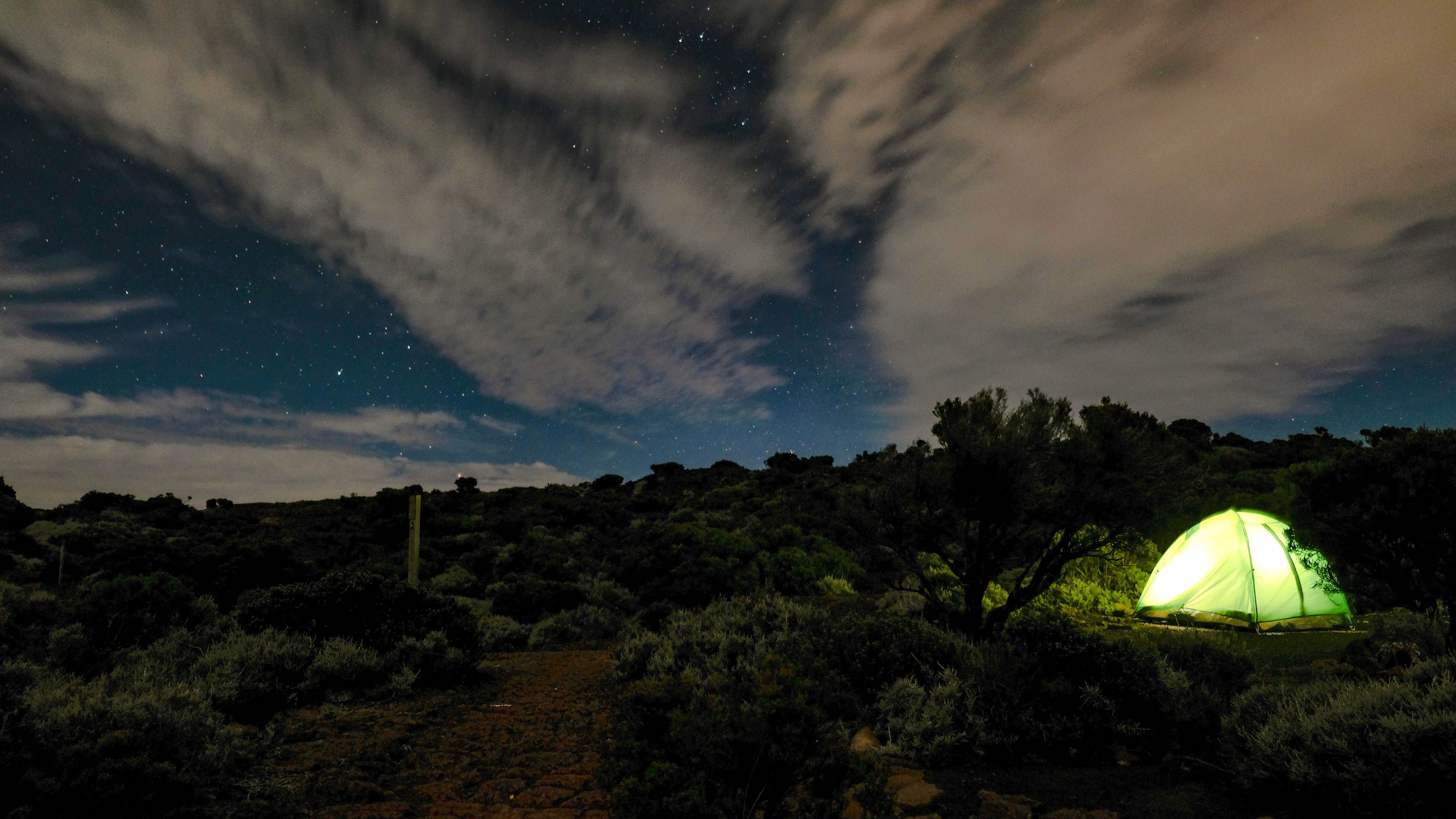 A serene camping scene under a starry night sky in Réunion's rugged wilderness.