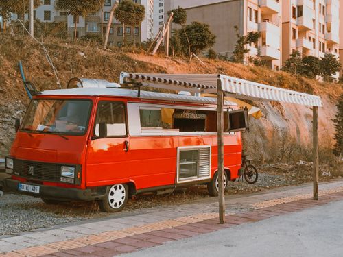 Free A vibrant red food truck parked on an urban roadside in Türkiye under a striped awning. Stock Photo