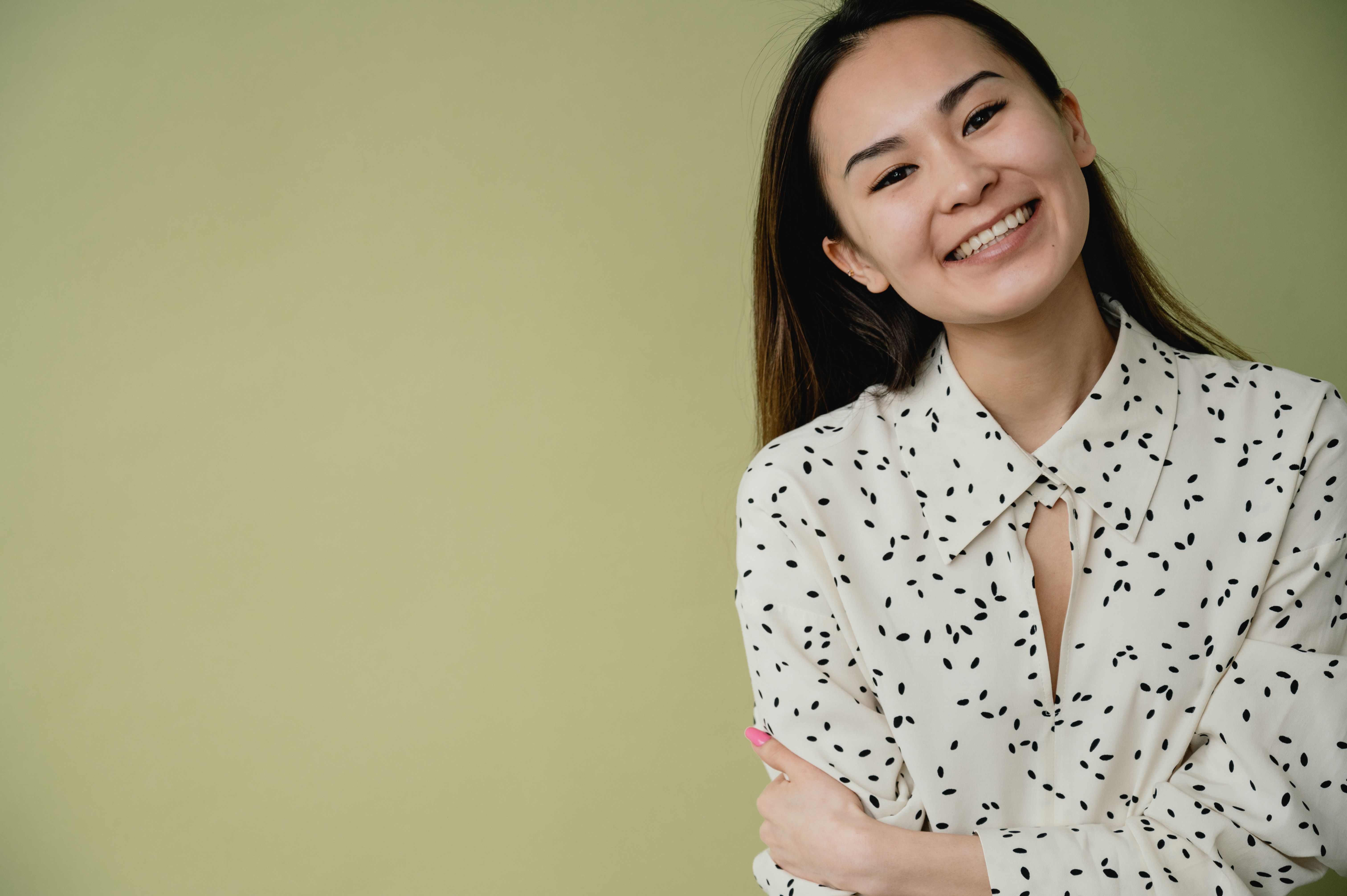 Smiling woman in her thirties in a white patterned dress.