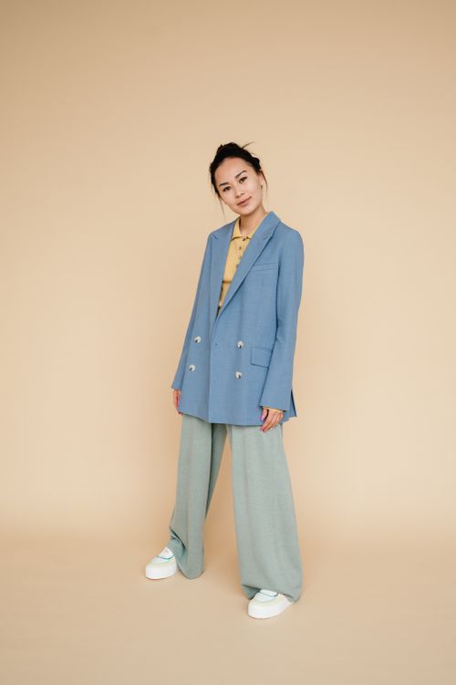 Free Stylish woman in a blue suit and baggy pants on a yellow background. Stock Photo