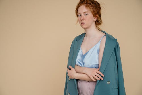 Portrait of a Redhead Woman with Turquoise Coat on Beige Background