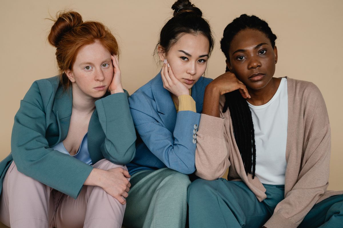 Three women in relaxed tailoring against a warm studio backdrop — photo by SHVETS production on Pexels