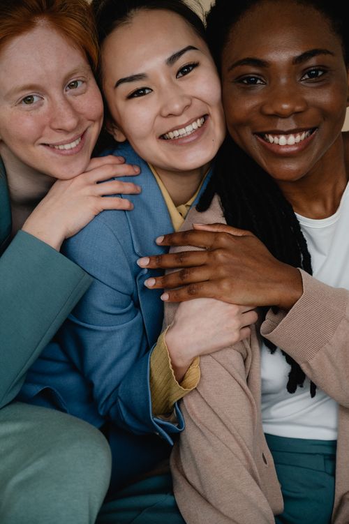 Free Three diverse women smiling and embracing, symbolizing friendship and unity. Stock Photo