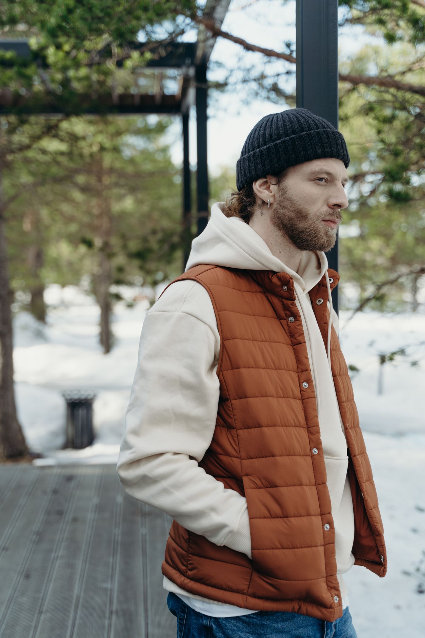 A man in a rust-brown quilted vest over a hoodie outdoors in the snow