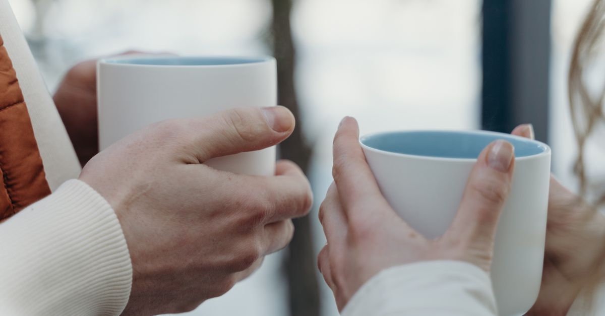 close-up of two hands holding coffee cups in conversation