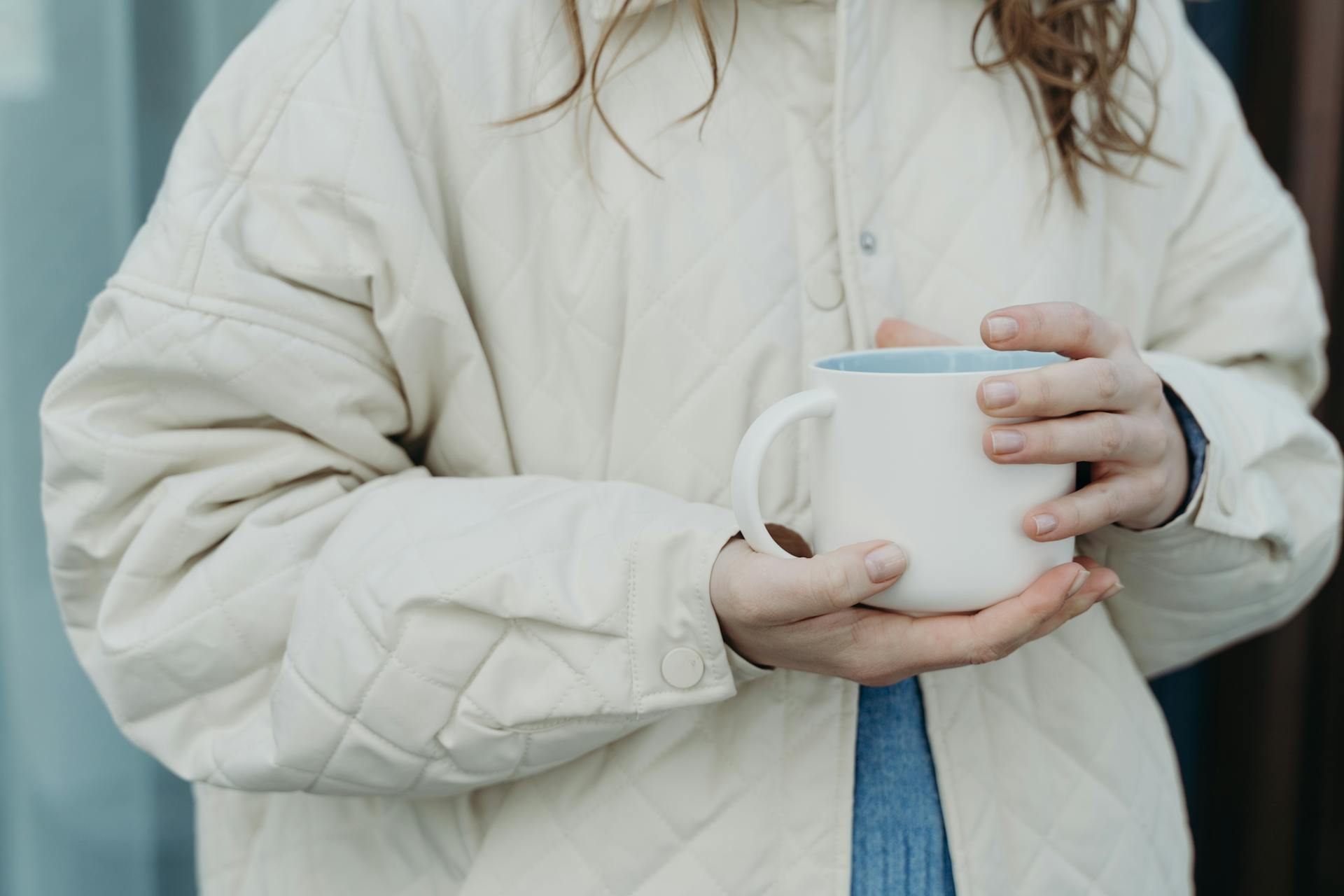 Close-up of hands holding a ceramic mug filled with hot tea on a cool winter morning.