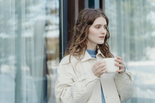 Free Woman in Beige Coat Holding White Ceramic Mug Stock Photo