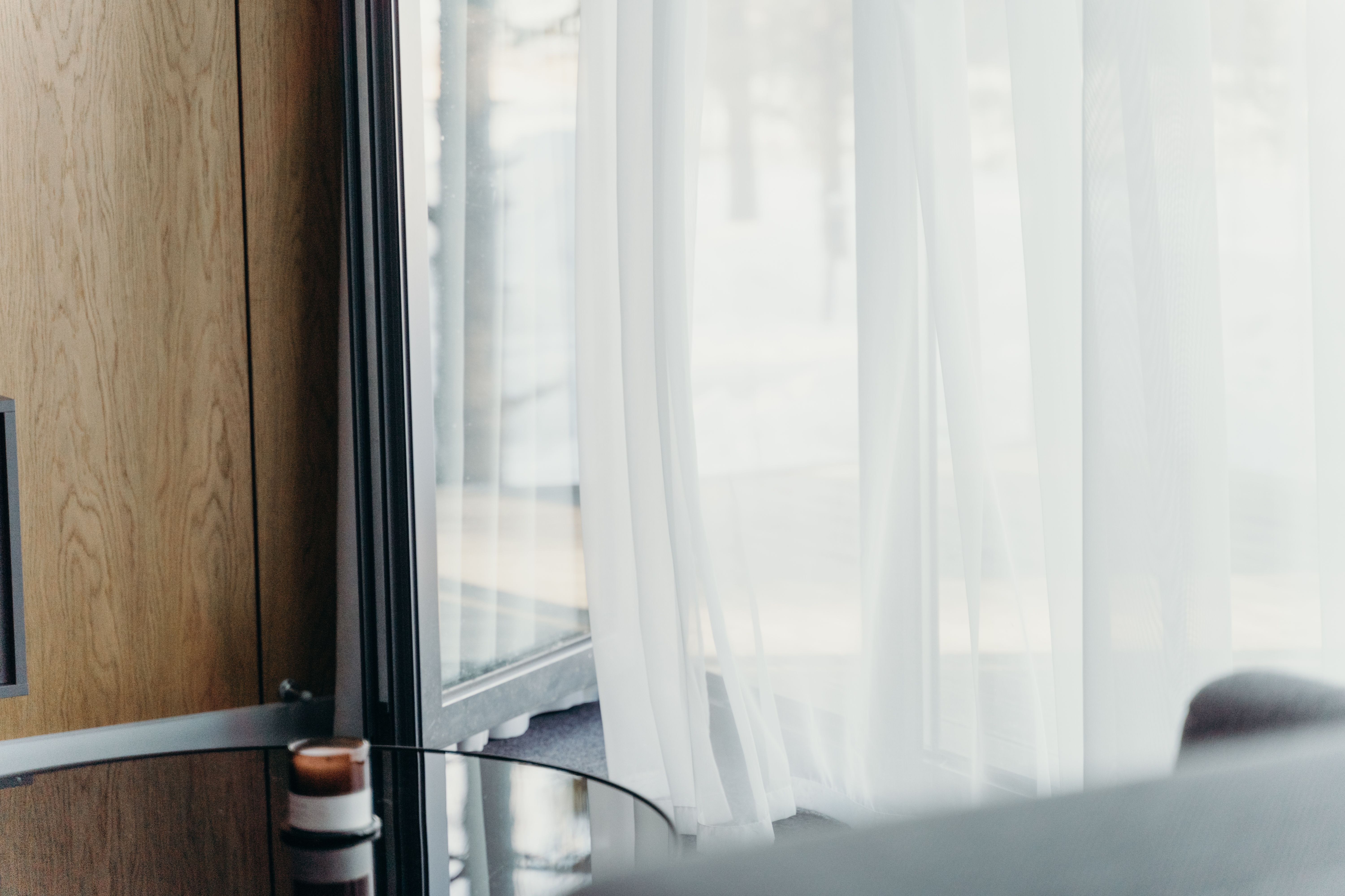 A modern hotel room with sheer curtains softly lit, emphasizing luxury and tranquility.