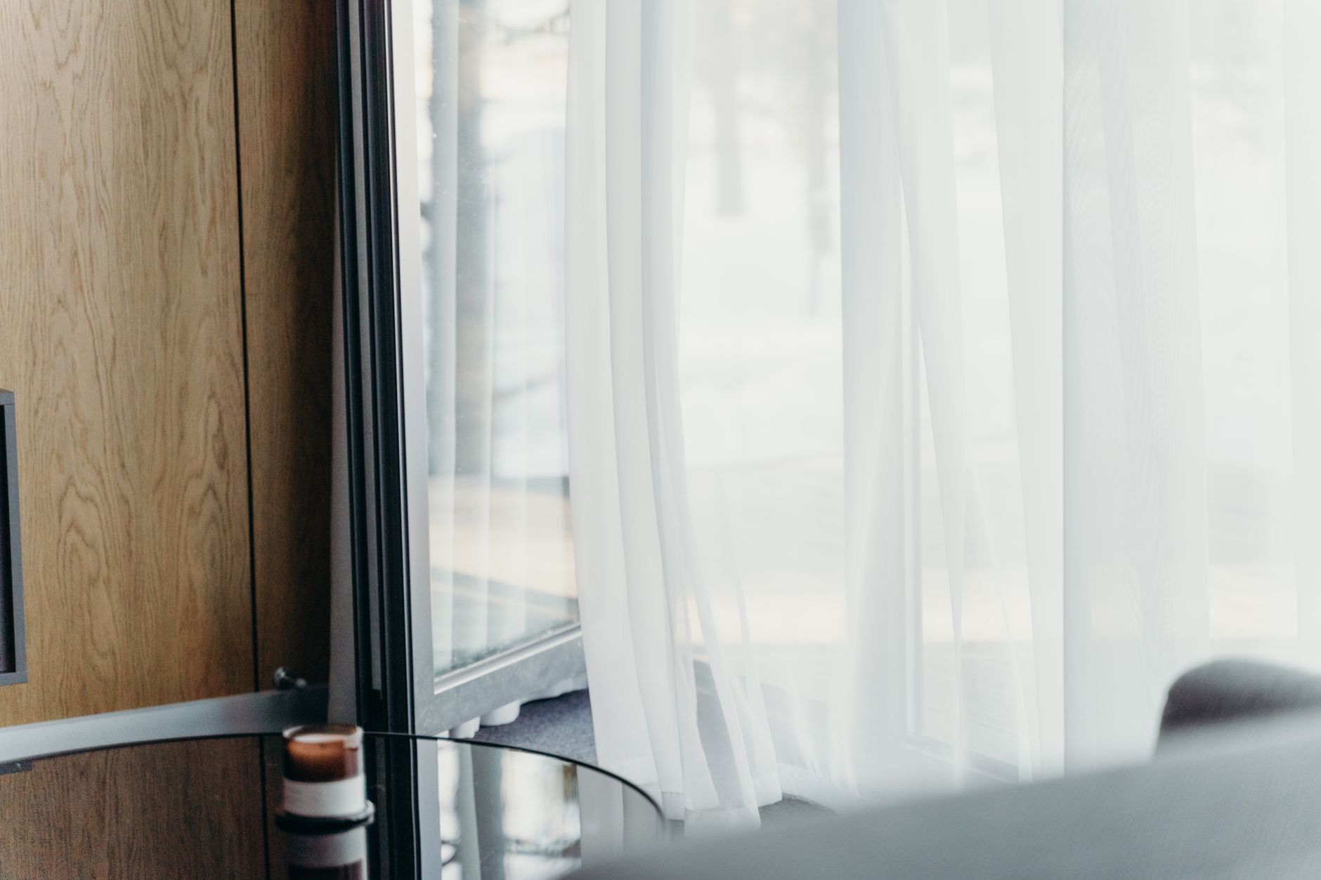 想要不透又有光,窗簾材質怎麼挑 A modern hotel room with sheer curtains softly lit, emphasizing luxury and tranquility.