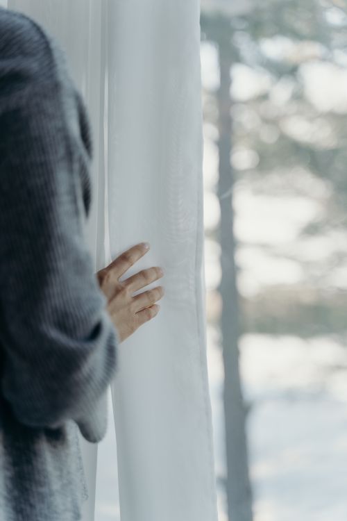 Free A tranquil moment with a hand gently touching a white curtain, bathed in soft daylight. Stock Photo