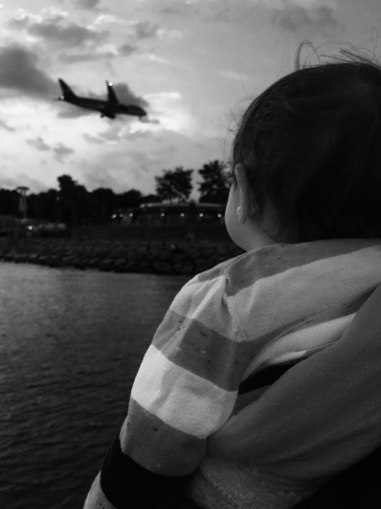 Grayscale Photo Of Baby Looking At An Airplane