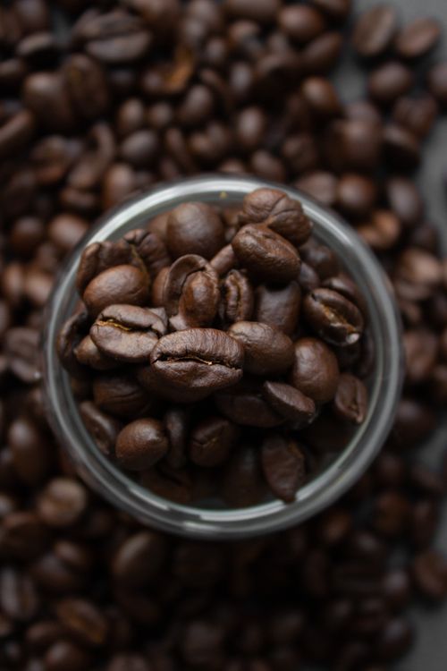Free Top view of pile of aromatic roasted coffee beans in glass jar and scattered on table Stock Photo