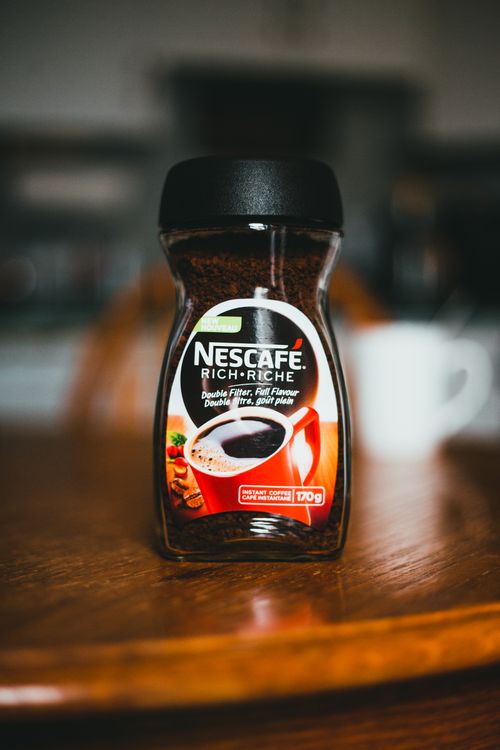 Free Closeup of glass jar with instant coffee placed on wooden brown table in kitchen Stock Photo