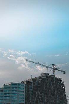 High-rise construction site with tower crane against a clear blue sky.