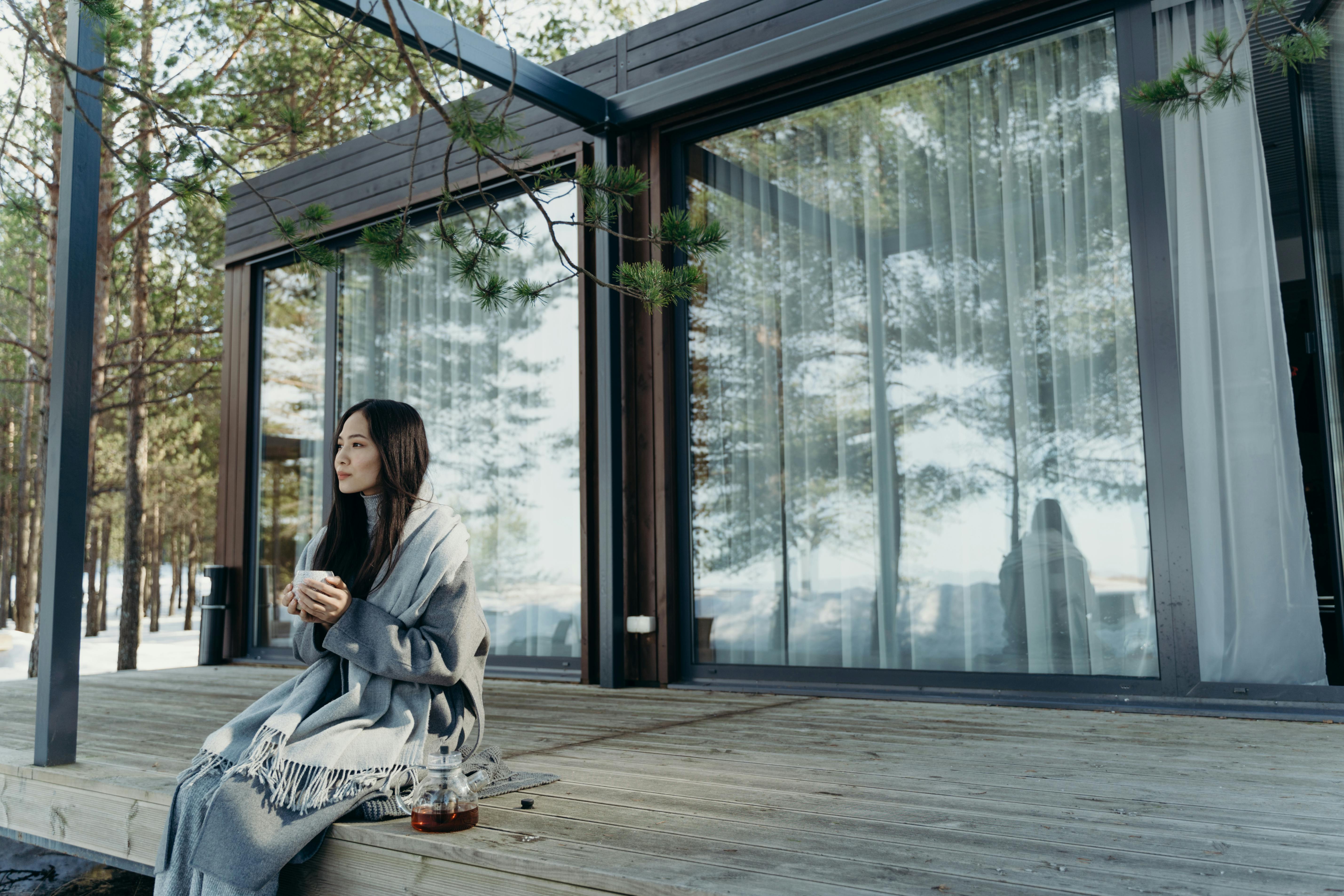 Asian woman enjoying a hot drink on a peaceful winter morning outdoors.