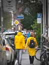 Man in Yellow Jacket and Gray Pants Walking on Sidewalk