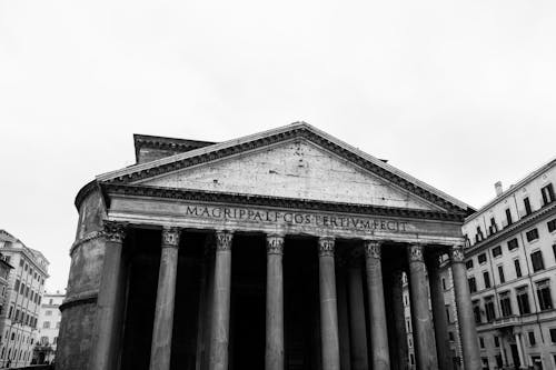 Free Ancient Roman temple facade between buildings in city Stock Photo