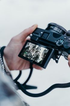 A close-up shot of a person holding a camera, capturing an outdoor scene on a digital display.