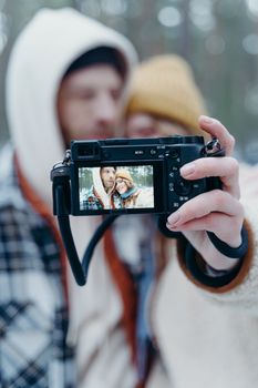 A couple enjoys a winter day outdoors, capturing their moment with a mirrorless camera.