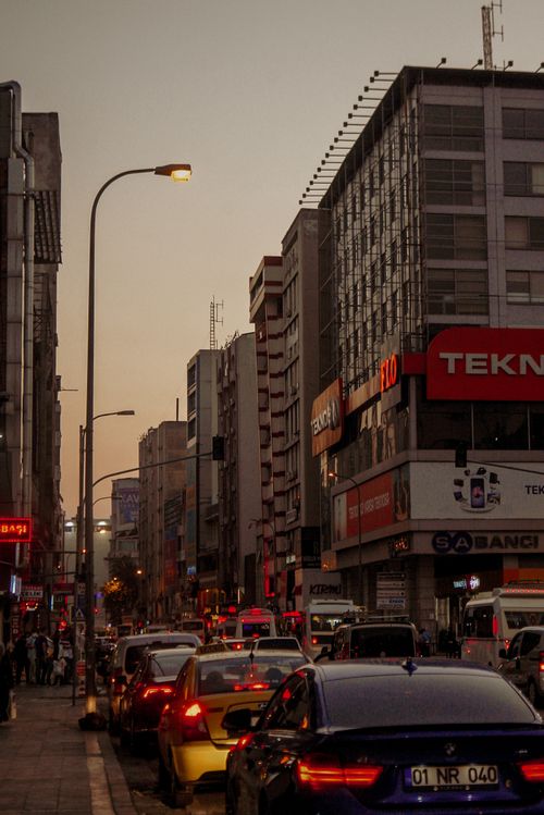 Free Urban street scene during rush hour with cars and buildings at sunset in a bustling city. Stock Photo