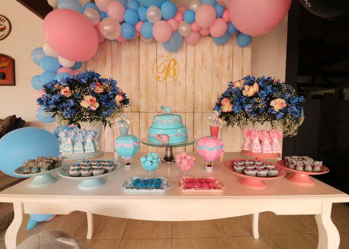 Gender reveal dessert table with pink and blue balloons