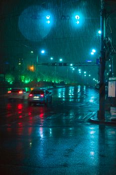 Cars driving on a wet road under traffic lights in rainy Ulaanbaatar night.