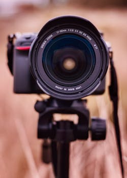 Close-up shot of a camera lens on a tripod with blurred background.