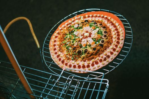 A colorful gourmet pizza with unique toppings, artistically presented on a metal rack. Perfect for food enthusiasts.