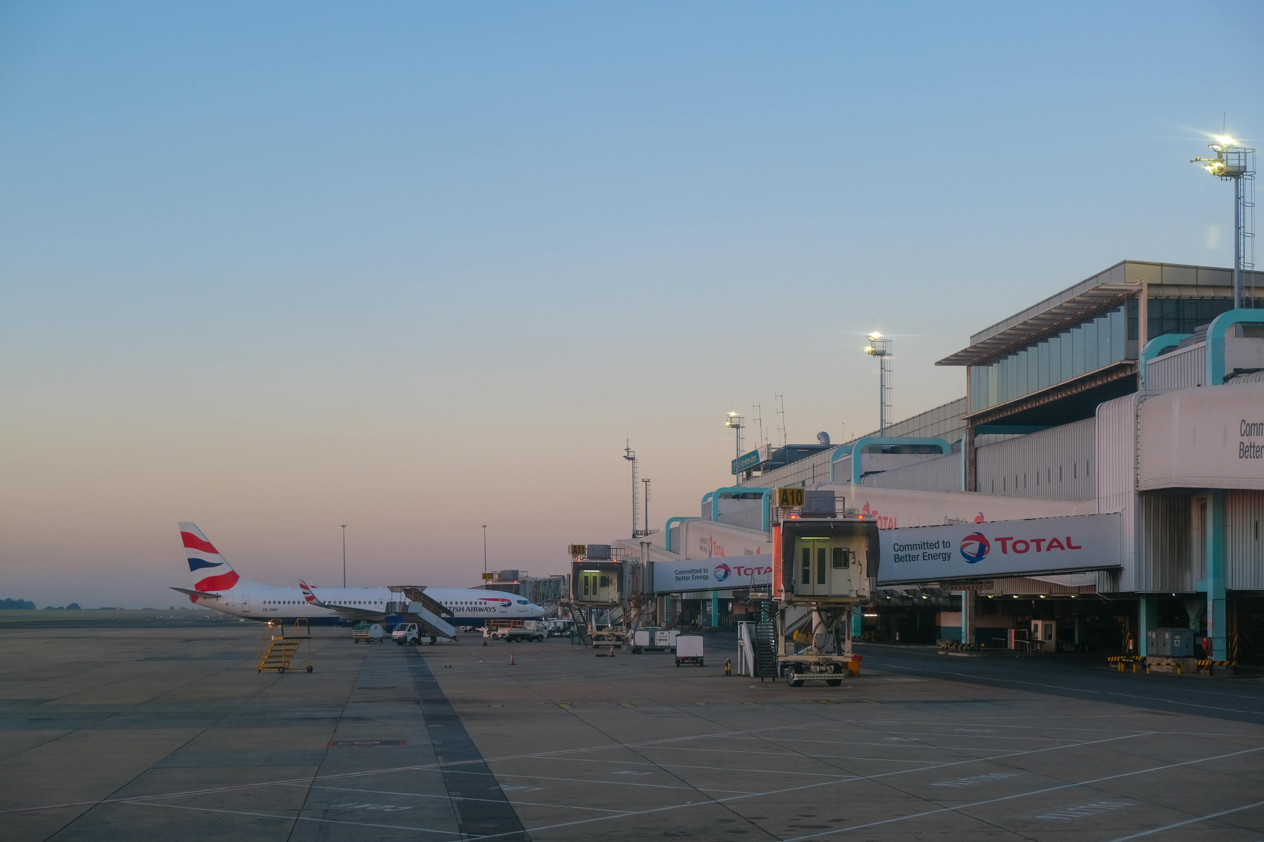 Free Sunset view of airplanes at the airport terminal with boarding bridges. Stock Photo