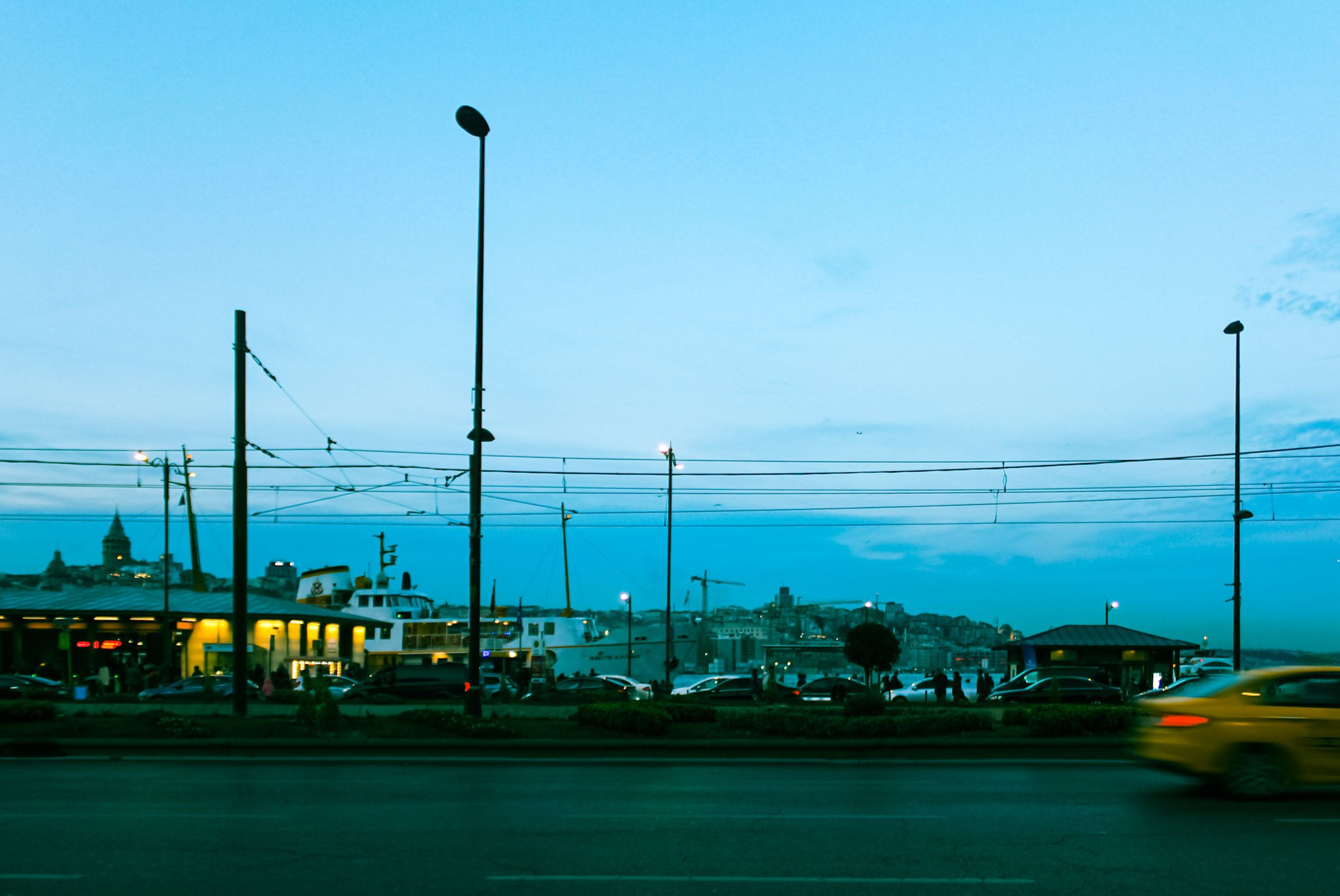 Street scene in Fatih, Istanbul featuring Galata Tower and city lights at dusk.