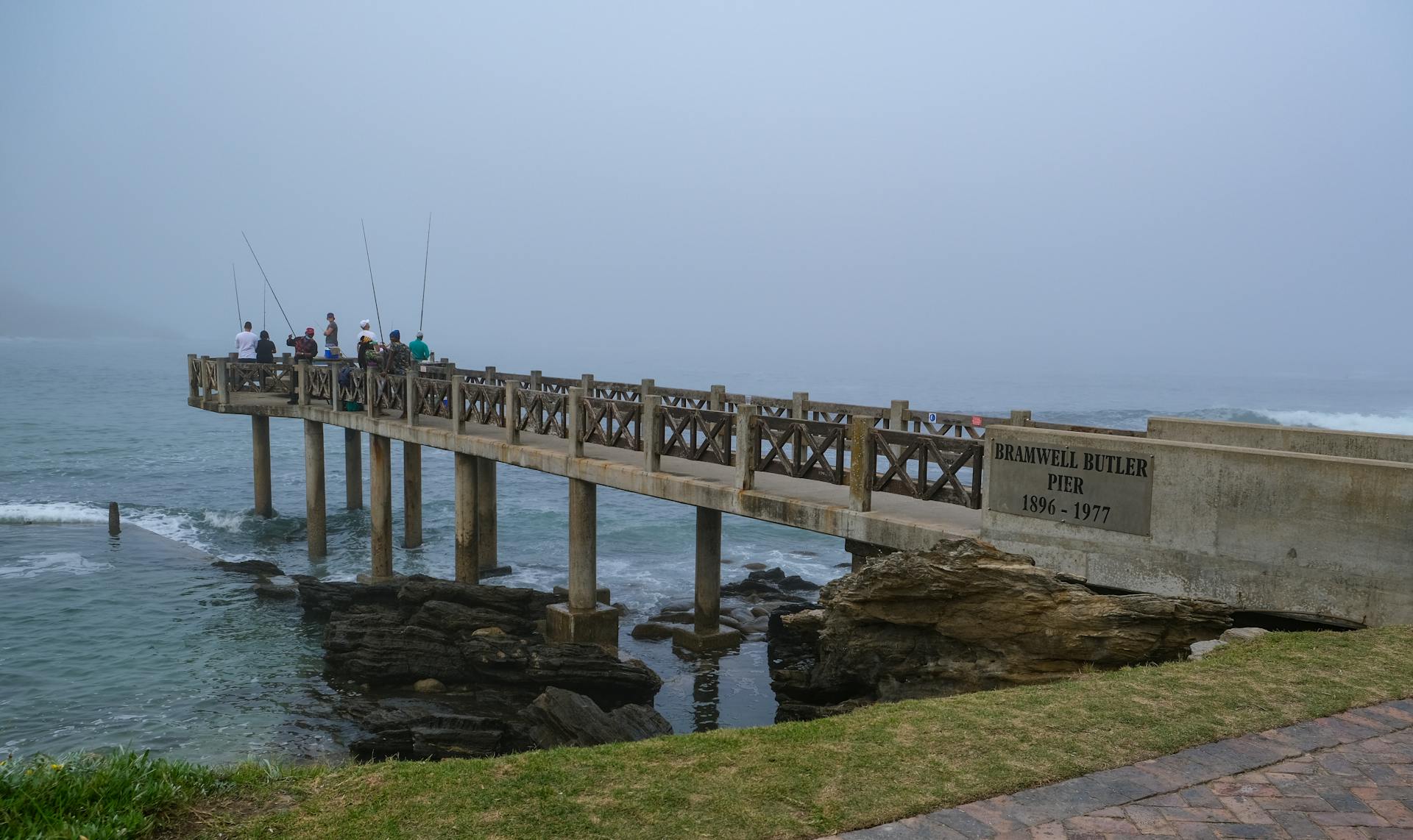 A group of fishermen enjoys a foggy day on Bramwell Butler Pier, capturing a serene moment at sea.