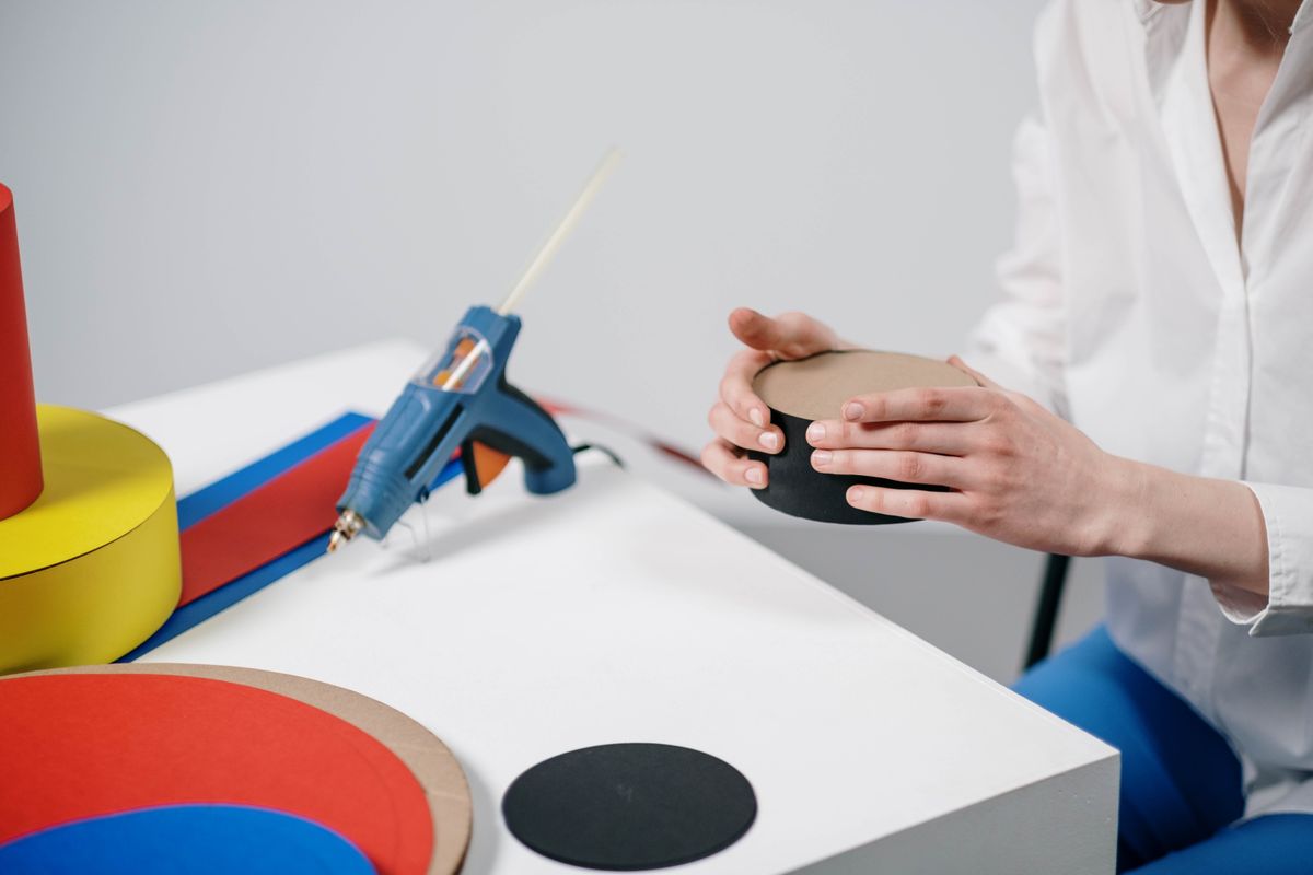 Hands crafting layered paper greeting cards with a glue gun indoors