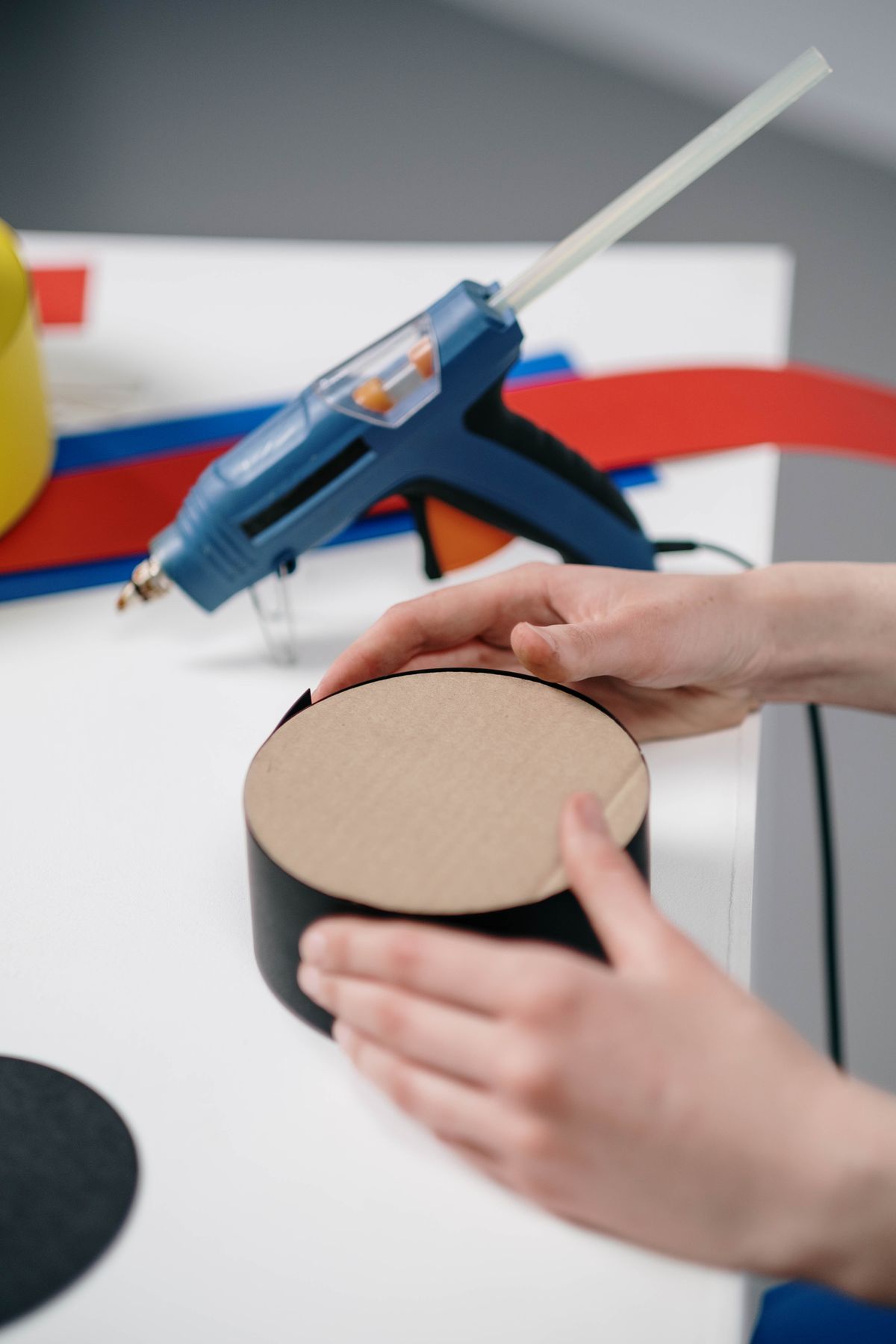 Hands gluing cardboard pieces together to build a mini playhouse
