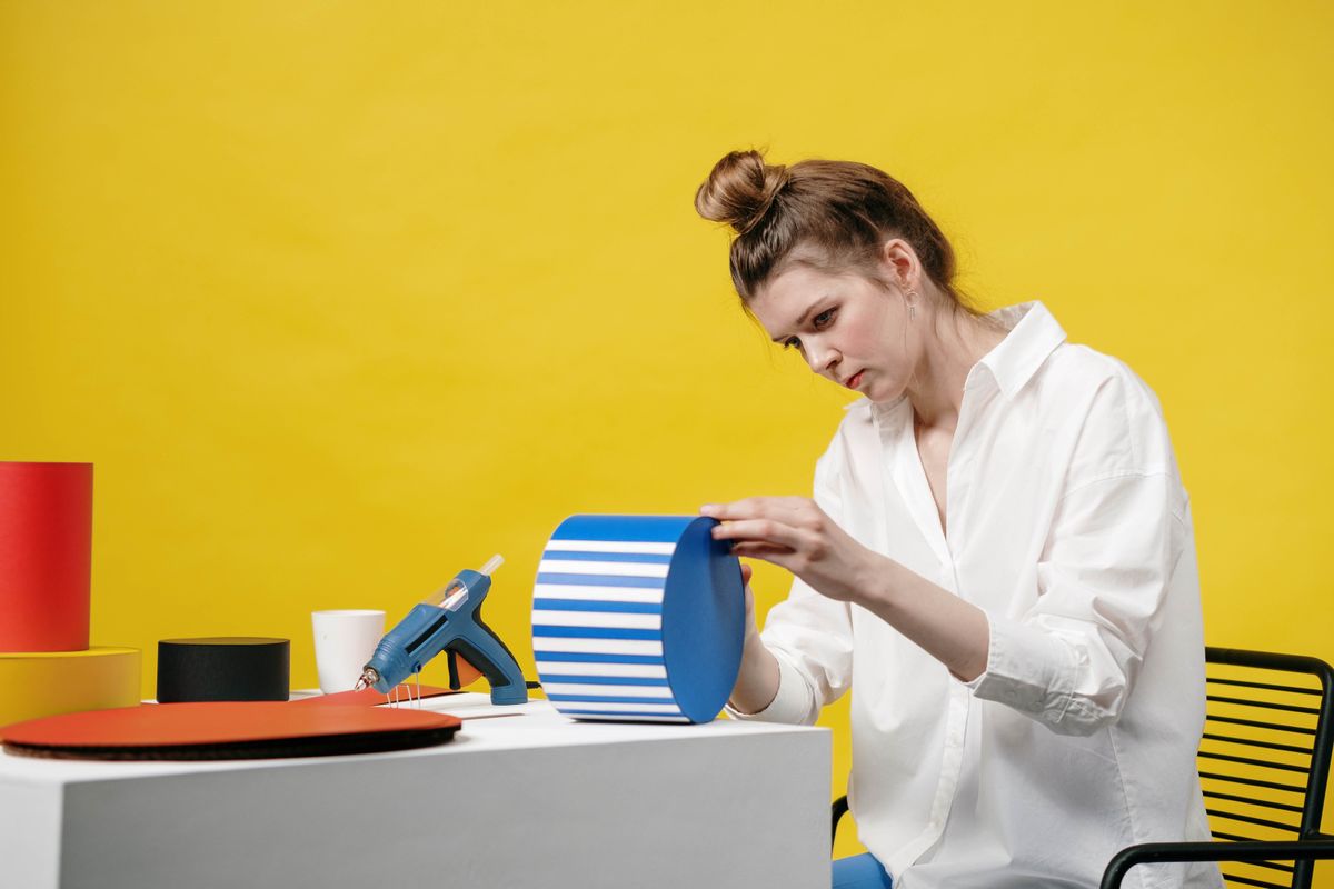 Woman gluing paper flags for a party banner at a yellow backdrop studio
