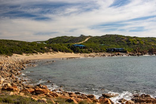 Beautiful coastal landscape with rocky shoreline and lush greenery under a blue sky.