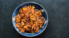 一碗充满活力的辛辣辣椒油，配有大蒜和胡椒片，非常适合为餐食增添风味