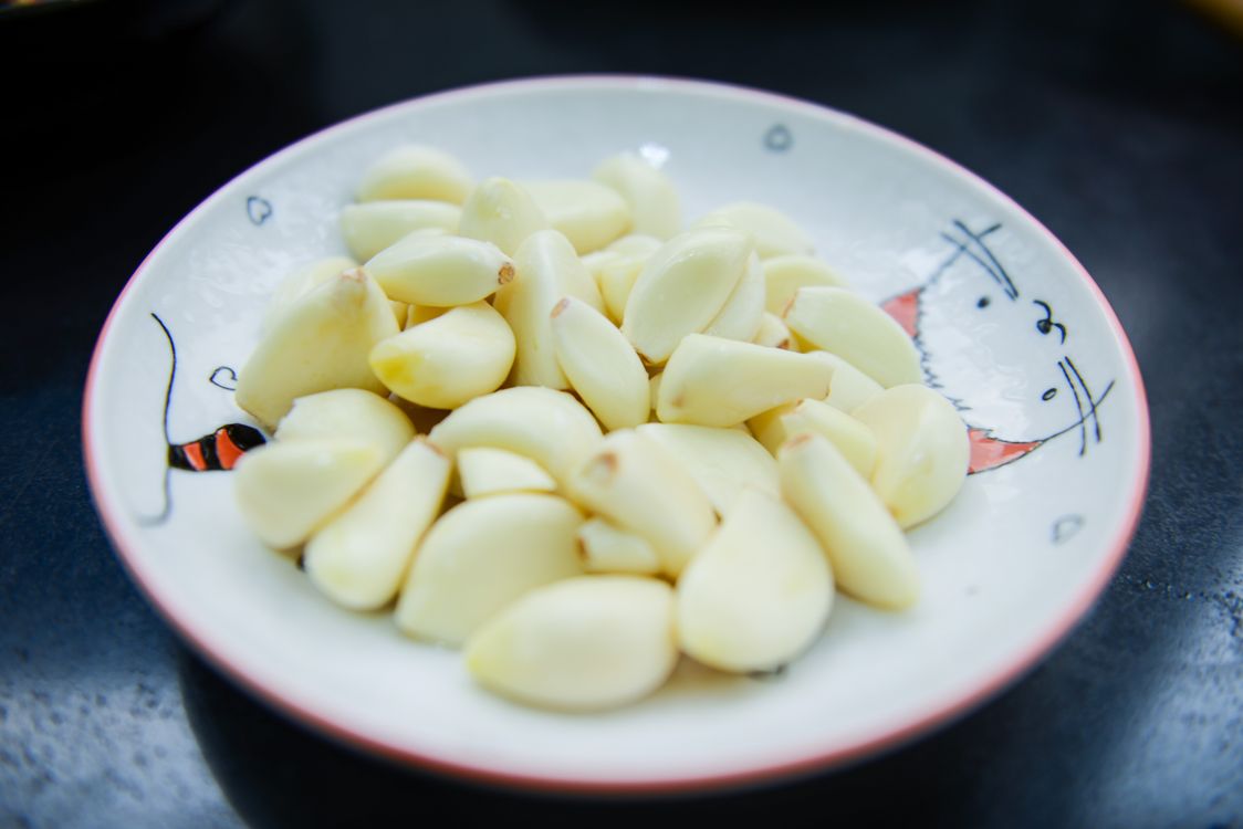 Free A close-up photo of peeled garlic cloves arranged on a decorative plate, highlighting their freshness. Stock Photo