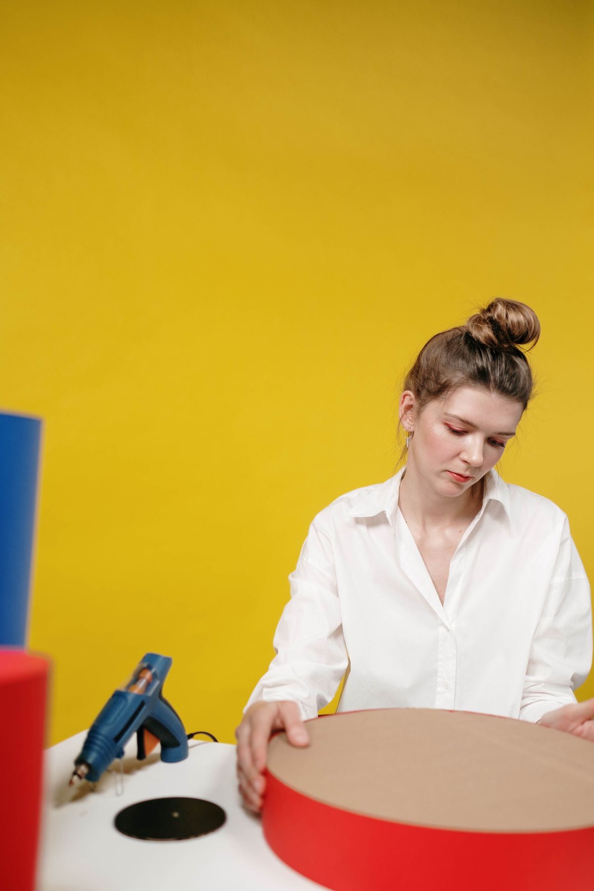 Woman creating large cardboard wall letters with a glue gun in a studio