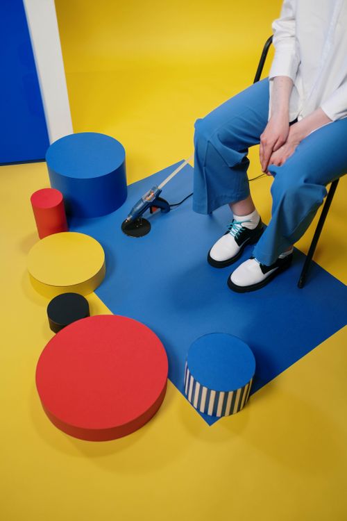 Free Person sitting among vibrant geometric shapes in a studio. Stock Photo