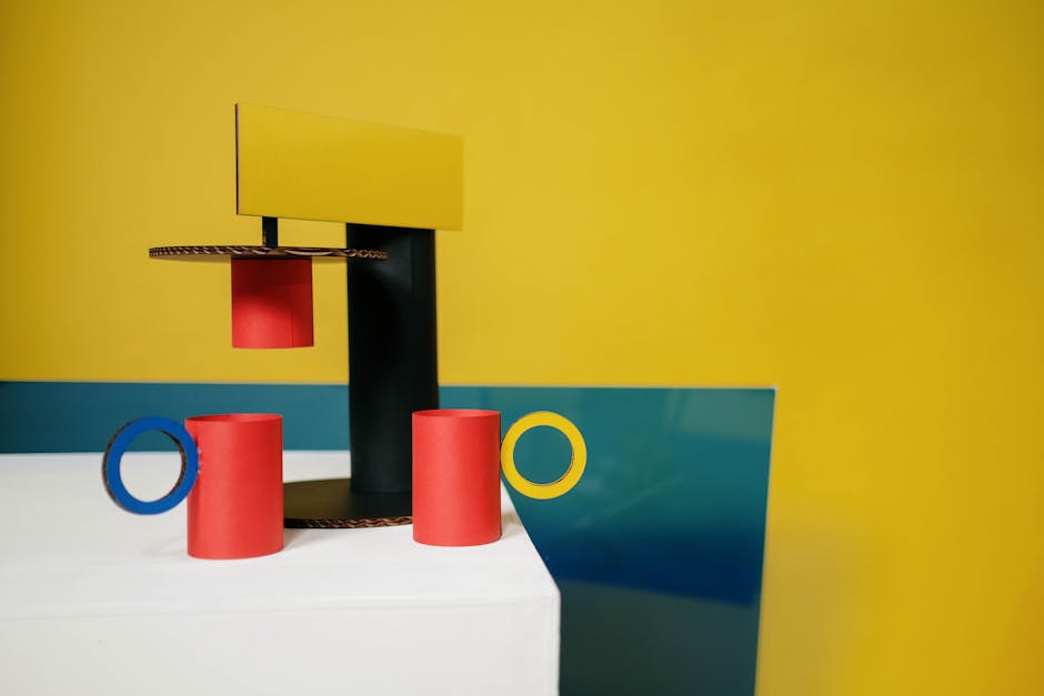 Creative cup and coffeemaker made of colorful cardboard and paper placed on white table against two colored background