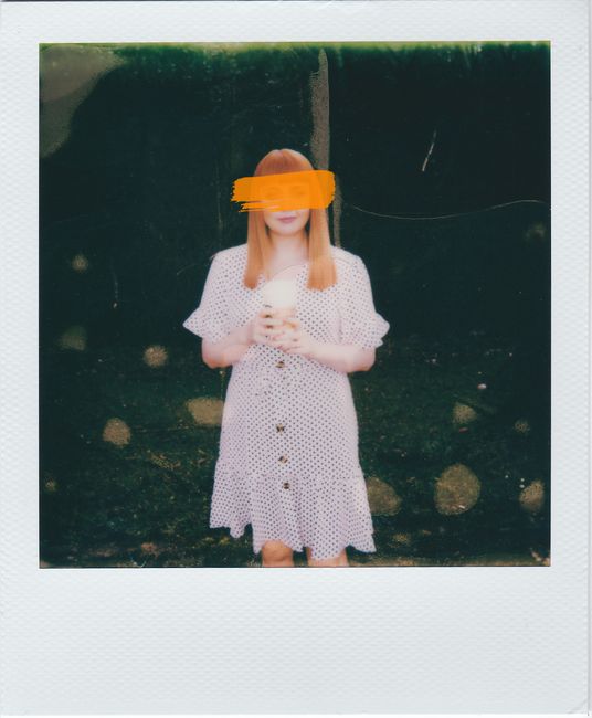 Vintage Polaroid of a red-haired woman in a polka dot dress holding a cup.