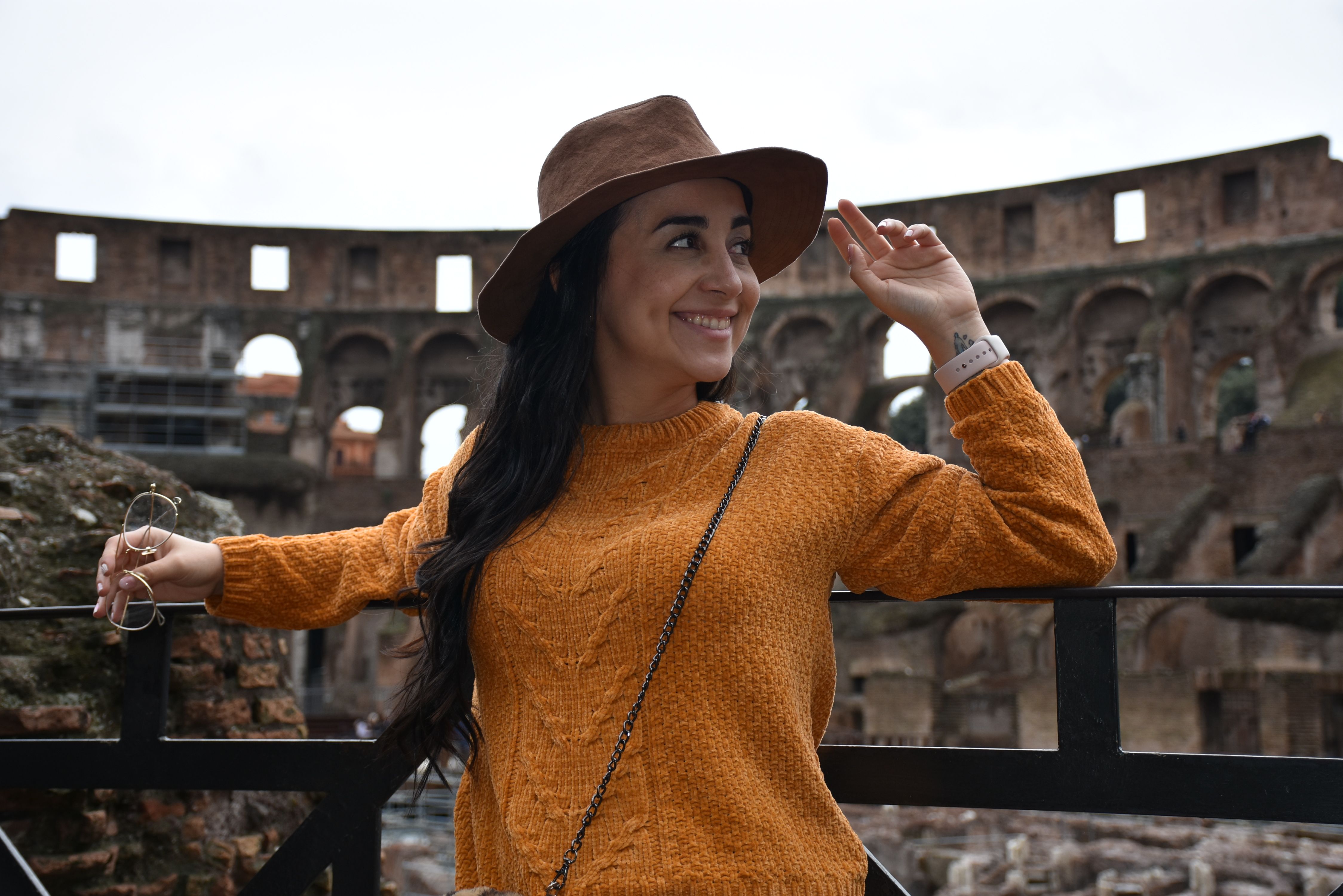 A young woman in a hat enjoys a sunny day at the iconic Colosseum in Rome.