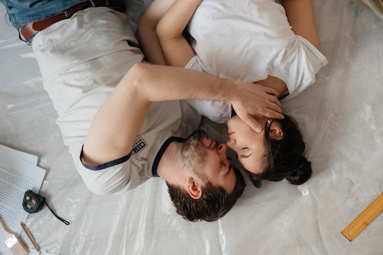 A Couple Kissing While Lying On The Floor