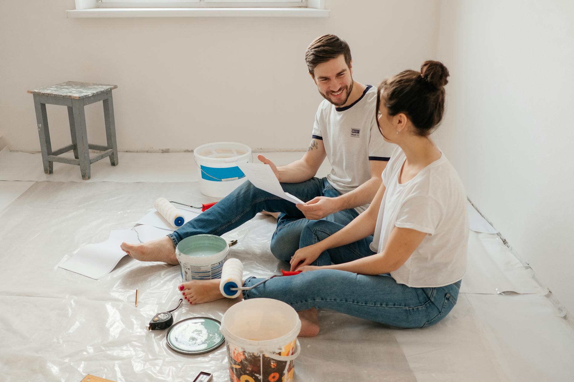 Young couple enjoying a home renovation project with paint supplies indoors.