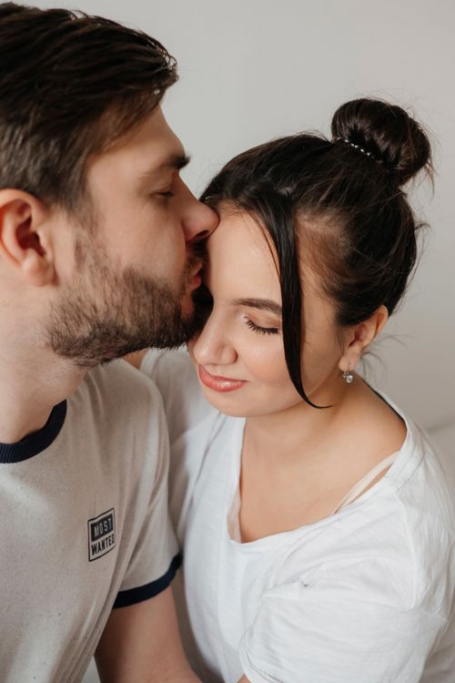 Free A close-up of a couple sharing a tender moment and a kiss indoors, expressing love and connection. Stock Photo