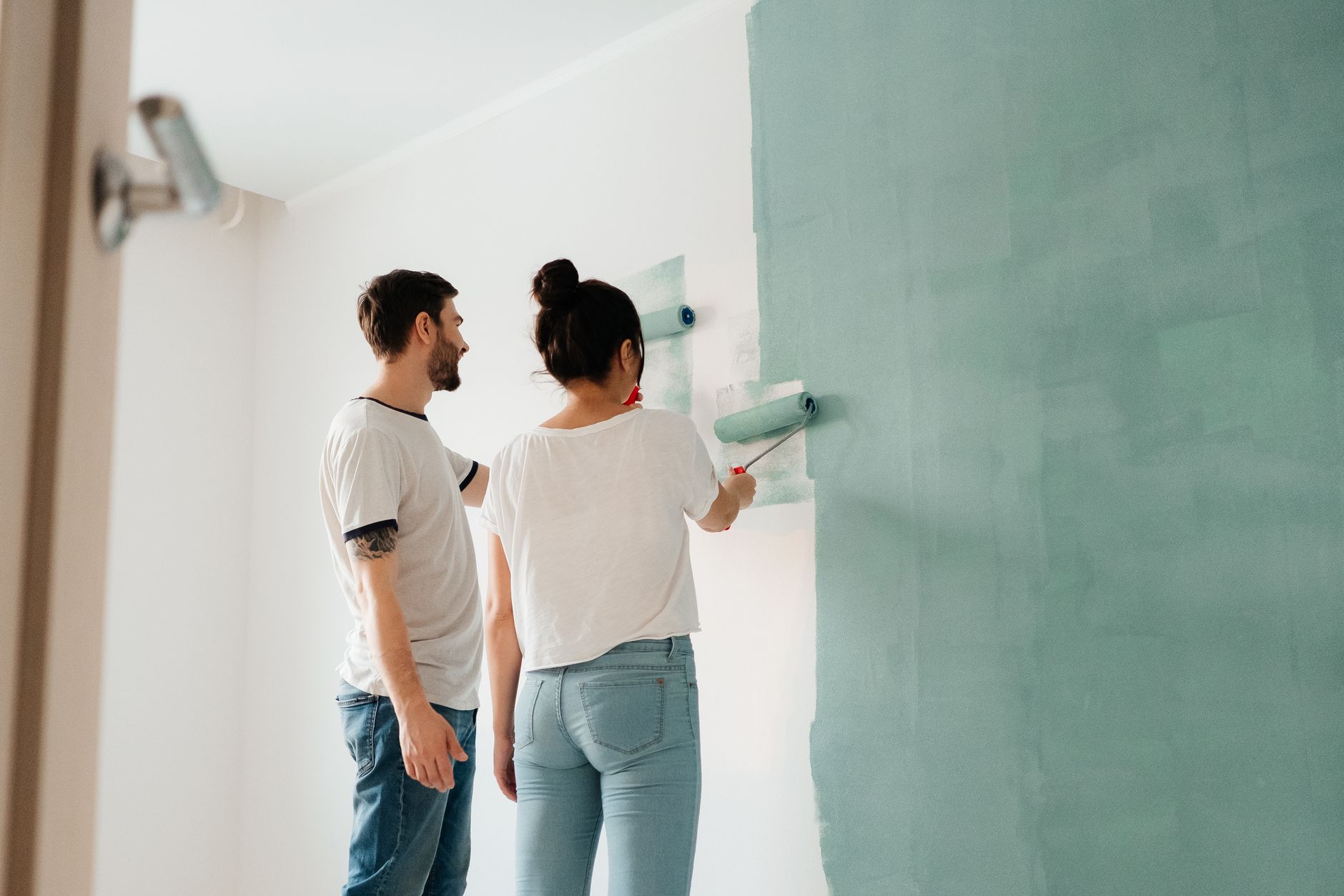Interior House Painting Cost in Chanhassen for 2026 3 A couple collaborates to paint a wall with a roller indoors, showcasing teamwork.