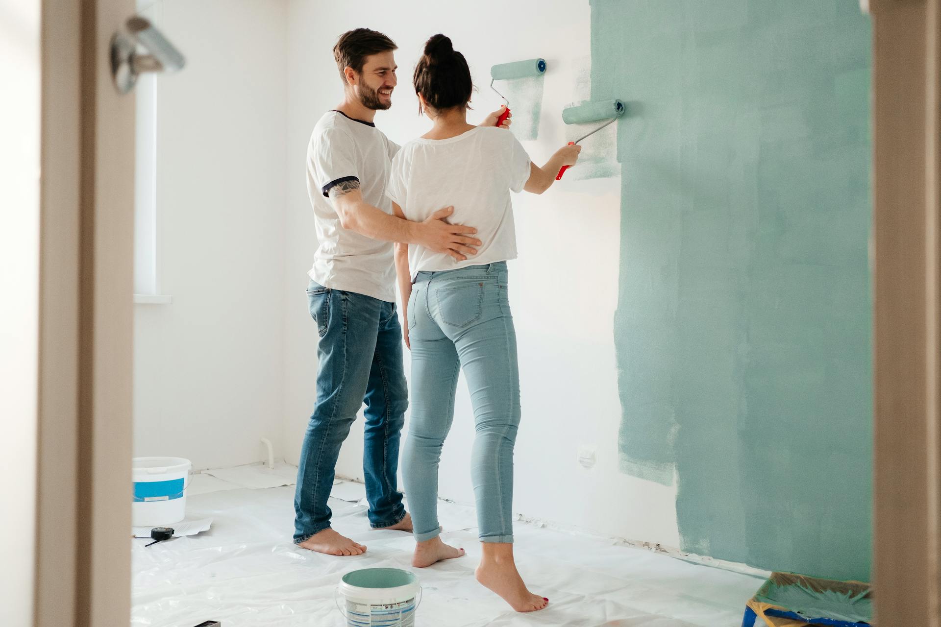 A couple painting a room together, focusing on home renovation and bonding.